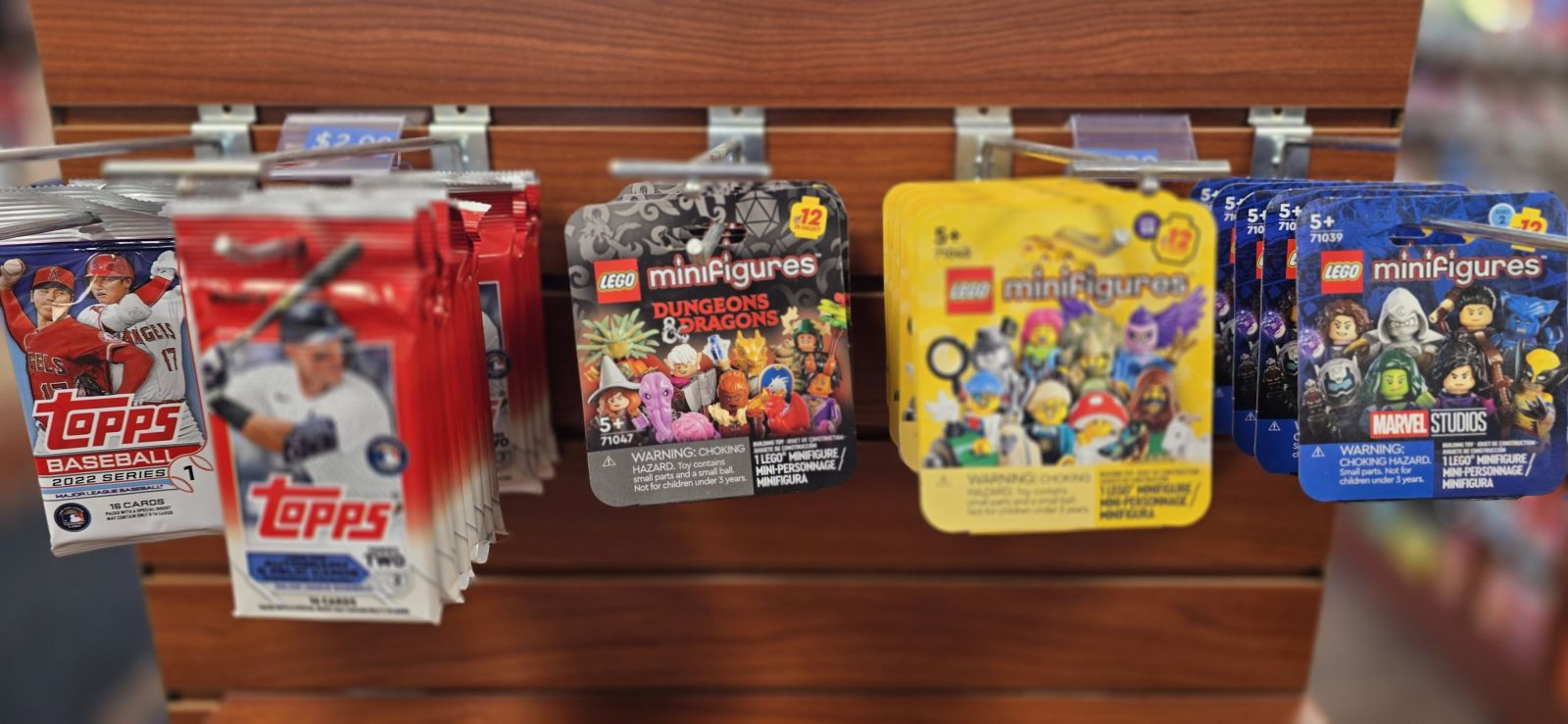 20241023_115445 Trading cards and LEGO minifigures packs hanging on display hooks in a store.