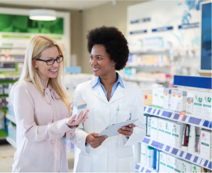 25-50-3 A pharmacist helps a smiling customer choose a product in a brightly lit pharmacy.