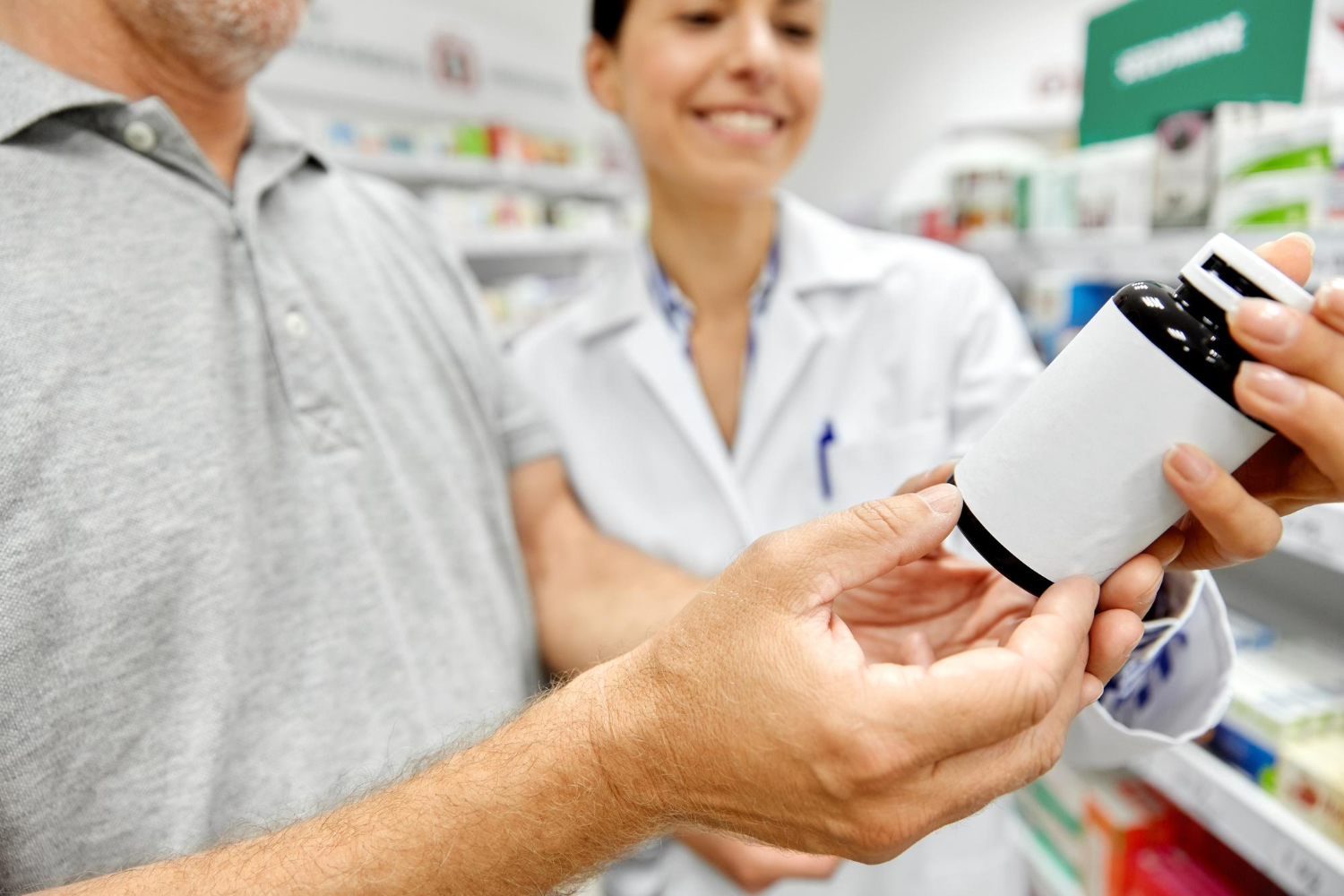 264045 A pharmacist shows a medication bottle to a customer in a pharmacy.