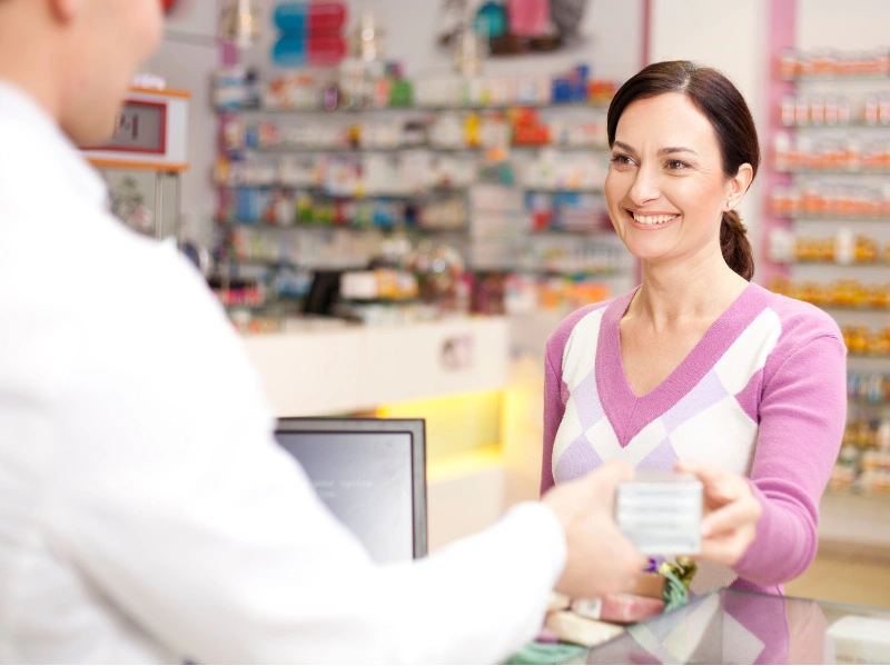 convenience A pharmacist assists a customer at a pharmacy counter with shelves of products in the background.